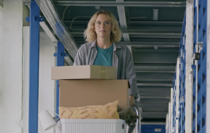 Woman pushing a trolley loaded with boxes through the clean indoor corridors at Boxxs Self Storage.